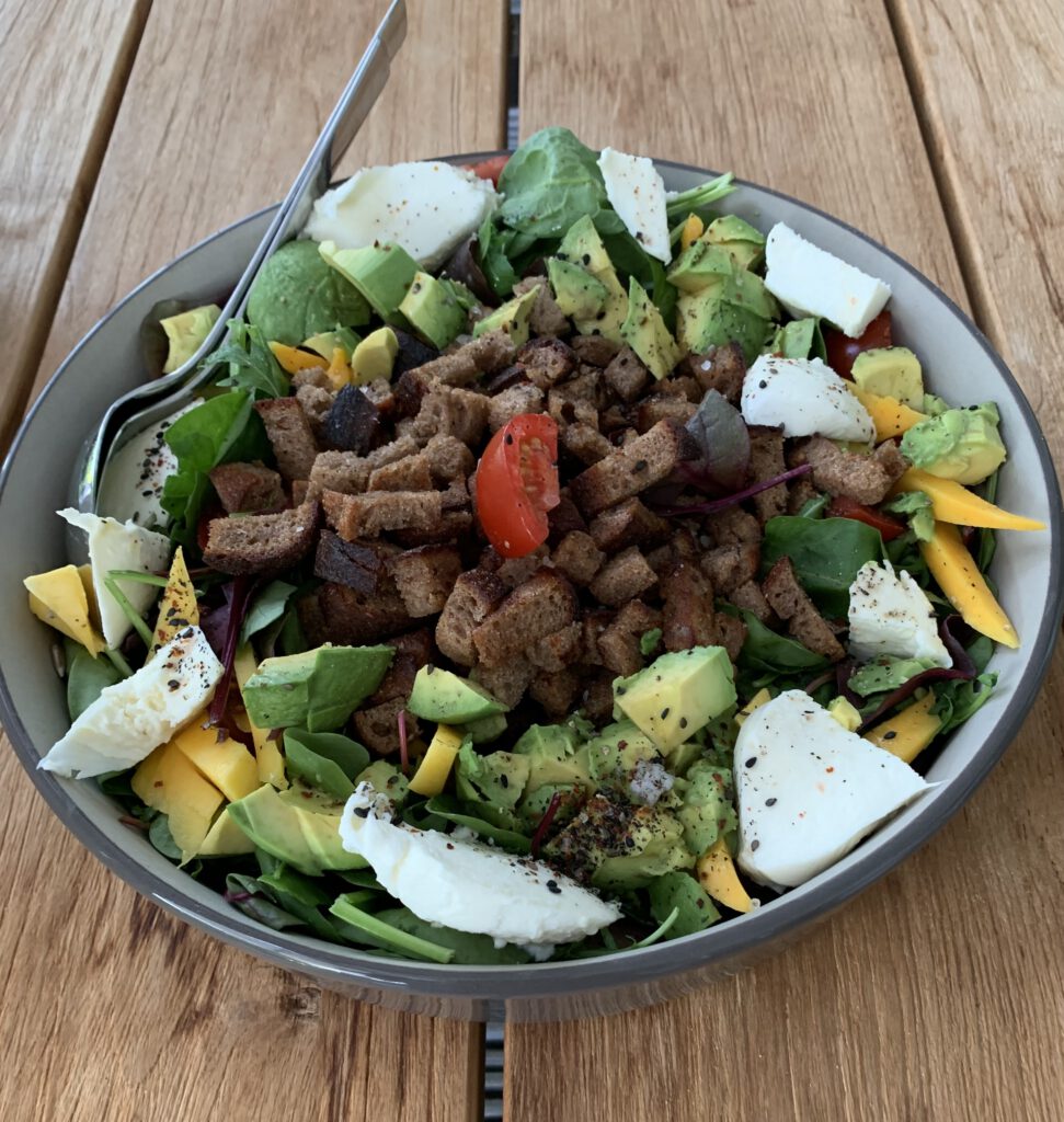 Ein Teller mit Brotsalat steht auf einem Holztisch.