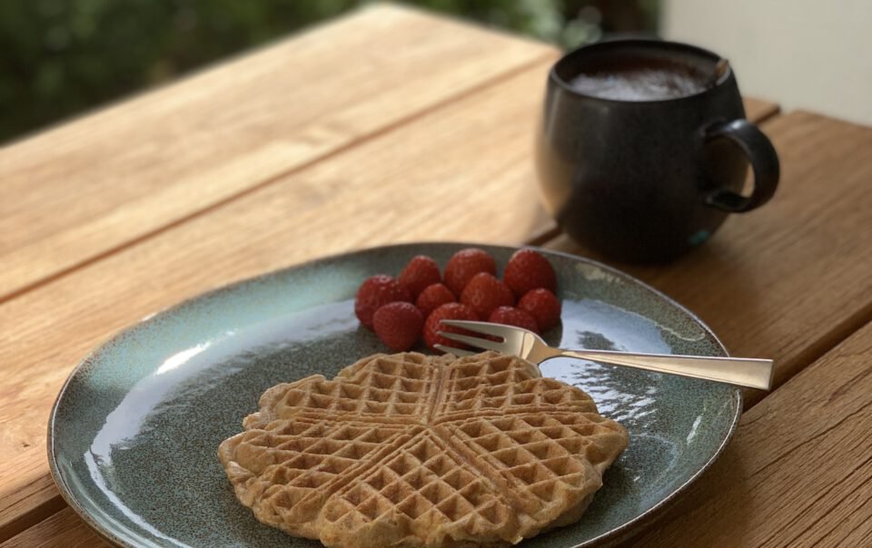 Vollkornwaffel auf einem Teller mit Himbeeren.