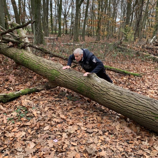 Andreas macht im Wald eine Liegestütze auf einem umgestürzten Baumstamm.