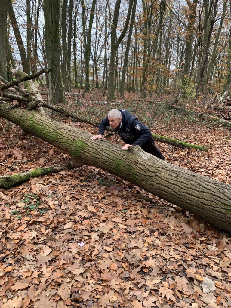 Andreas macht im Wald eine Liegestütze auf einem umgestürzten Baumstamm.