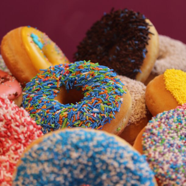 Verschiedene Sorten Donuts mit Zuckerguss liegen auf einem Tisch.